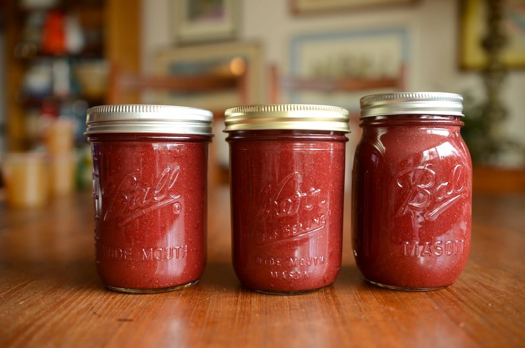 Three pint jars filled with finished strawberry hibiscus butter.