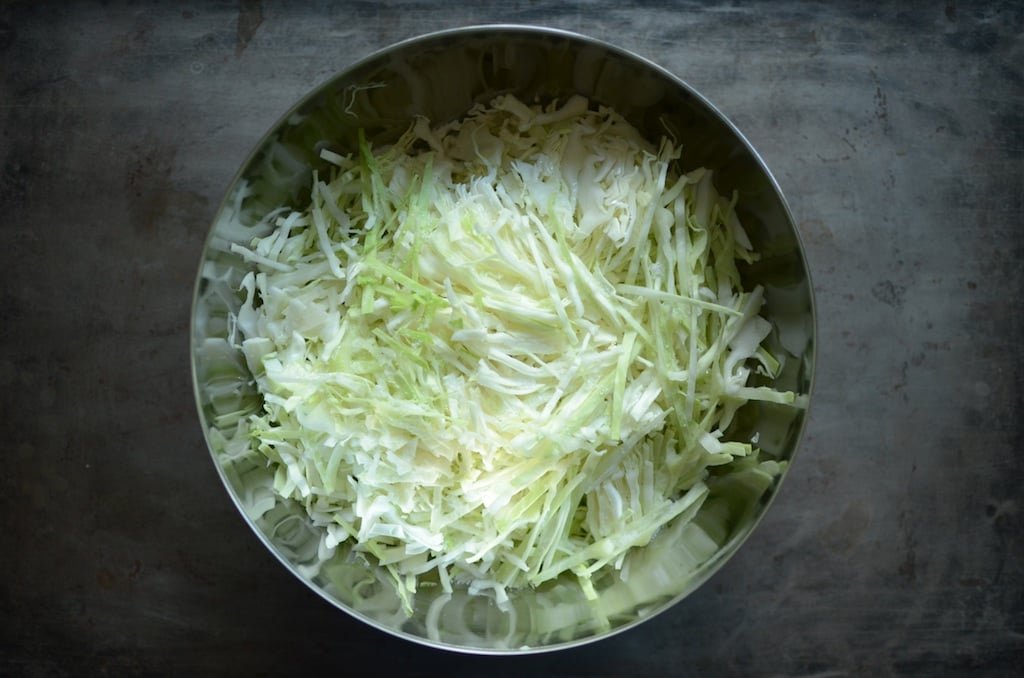 Metal bowl holding shredded green cabbage